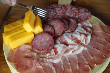 fork that takes mixed cold cuts from the wooden cutting board in