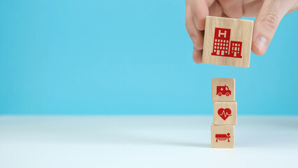 Wooden blocks with the healthcare medical symbol arranged a man is holding the top one.