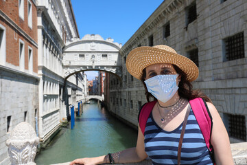 Fototapeta na wymiar Beautiful woman with surgical mask and straw hat and the bridge