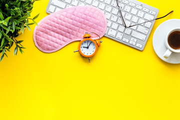 Hard exhausing work. Sleep mask on yellow office desk top-down copy space