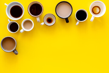 Different cups of coffee on yellow table top-down space for text