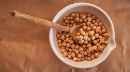 chick lies in a white mortar with a wooden spoon on a brown background