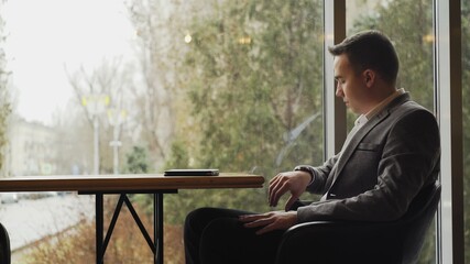 Fototapeta premium Handsome man waiting woman in restaurant and watching to clock