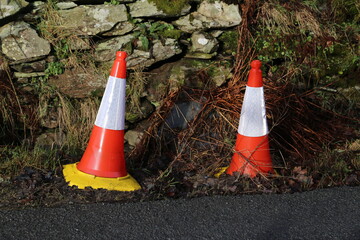 Orange and white reflective road cones indicating a ditch beside the road.