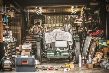 Retro vintage car covered by white cloth. Renovation project in the garage with lots of mechanical...