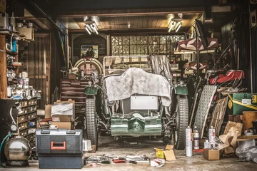 Poster Retro vintage auto bedekt met witte doek. Renovatieproject in de garage met veel mechanische details en gereedschappen © bzzup