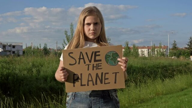 Serious teenage girl stands by the road with her own poster SAVE THE PLANET.