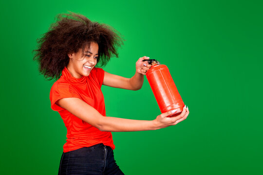 Dark-skinned Smiling Woman Holds A Red Fire Extinguisher On A Green Background In Studio