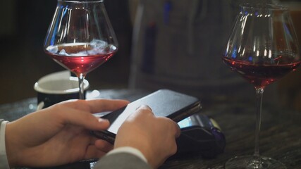 Man making payment through NFC technology on mobile phone in cafe