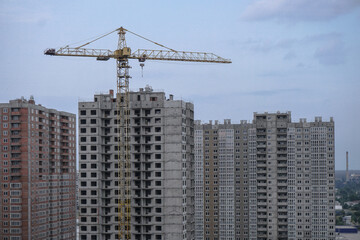Fototapeta premium Multi-stage construction during the construction process with a yellow crane. Industrial background for design.