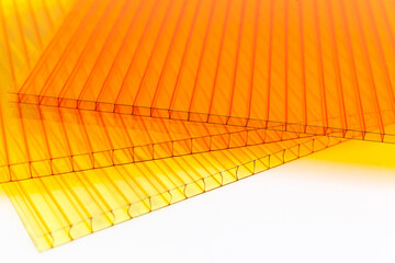 Polycarbonate plastic sheets panels images. PC hollow sheet for translucent roofing close up. Yellow, orange colors on white background