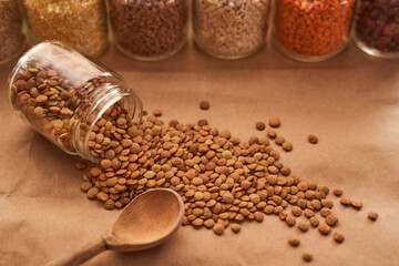 Lentils lie on a brown background with a wooden spoon