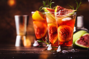 Red cocktail with cognac, liquor, lime juice, figs and honey, old wooden table, bar tools, copy space