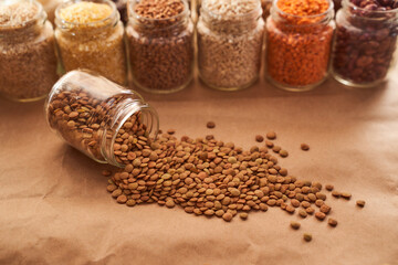 Lentils lie on a brown background with a wooden spoon