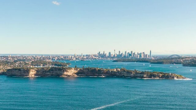 Stunning aerial drone hyperlapse of Sydney harbour area with many sailboats cruising. South Head and Watsons Bay in the foreground, Sydney skyline with Harbour bridge in the background.	