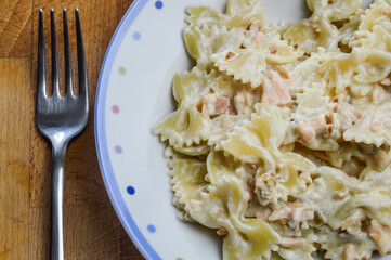 Farfalle pasta with smoked salmon and red onions in a cream sauce. Close up top view.