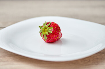 red ripe strawberry on a white plate