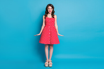 Full size photo of attractive pretty curly lady shiny pomade smiling white teeth good mood flirty wear summer red white dotted retro dress open toes shoes isolated blue color background