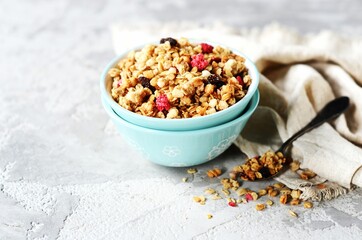 Homemade granola with berries and nuts in a bowl on a gray background