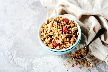Homemade granola with berries and nuts in a bowl on a gray background