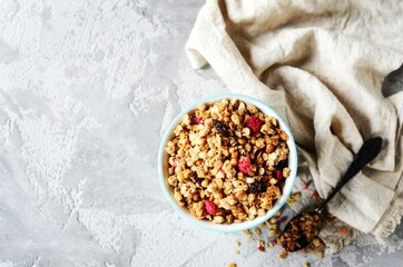 Homemade granola with berries and nuts in a bowl on a gray background