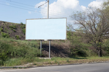road billboard, against the background of green trees of the road, an empty ad-free billboard along the road. Advertising, signboard, blank, pattern, copy space