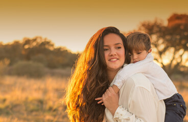 Beautiful woman playing with her son in the field at sunset. New families. Family lifestyle