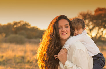 Fototapeta premium Beautiful woman playing with her son in the field at sunset. New families. Family lifestyle