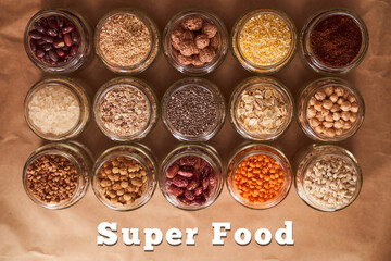 Super food grits in glass jars. Top view. lentils, chickpeas, corn, oats, beans, chia. With text Superfood