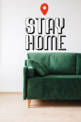 green sofa with pillow near stay home lettering