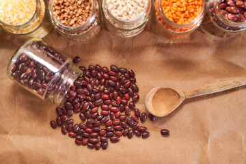 red bean beans crumbled from a glass jar on a brown background