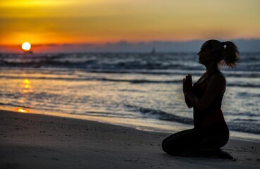 Fototapeta premium Woman doing yoga at the beach at sunset