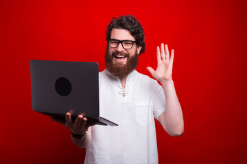 Photo of happy man talking online with someone on laptop and saluting