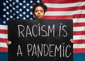 African american woman holding poster Racism is a pandemic
