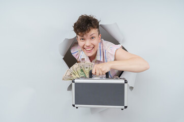 Pretty Woman is holding a suitcase full of money and emerging through torn paper hole in studio,...