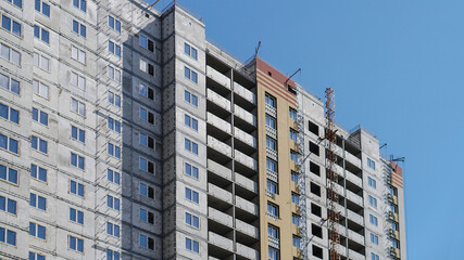 Large construction site on a background of blue sky. Brick, panel apartment building. Industrial theme for design