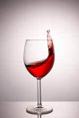 A splash of red wine in a glass on a white background