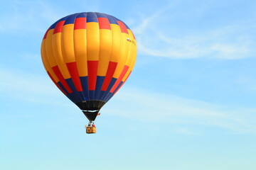 A hot-air balloon isolated in the sunny light-blue sky