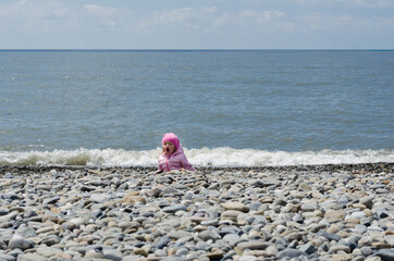 little girl on a stone beach at sea in spring