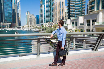 Portrait of a man 35-40 years old against the background of modern tall buildings. Adult Caucasian man against the backdrop of the city.