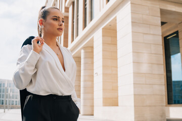 Business european elegant young woman fitting her cardigan clothes. Businesswoman goes to work in a...
