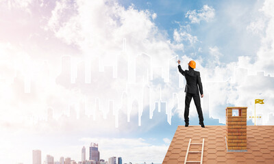 Man architect draw silhouette of modern city on blue sky. Mixed media