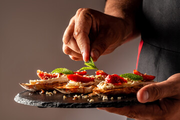 the chef cooks holiday crostini appetizers with brie cheese, strawberries and mint. Close up on a...