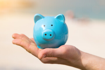 A man holds a piggy bank in his hand on his vacation A man holds a piggy bank in his hand on his vacation by the sea