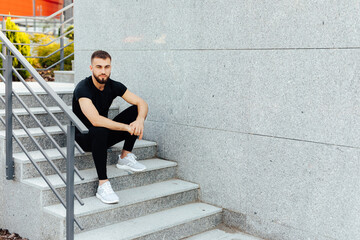 After Training. Cheerful man sitting on steps resting. Fit, fitness, exercise, workout and healthy lifestyle concept. free space for text.