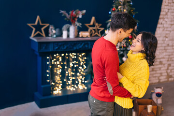 guy and girl in sweaters hugging and smiling. fireplace with dec