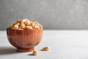 Cashews in a brown wooden bowl on a gray background with a copy of the space