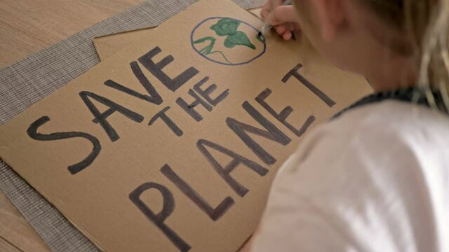 Schoolgirl makes a poster SAVE THE PLANET