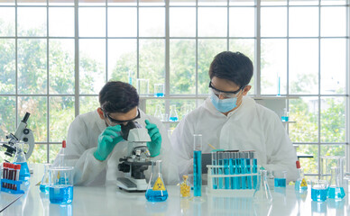 Asian Scientist working on blue test tube to analysis and develop vaccine of covid-19 virus in lab...
