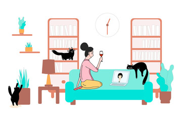 The stay at home concept.The girl is sitting on the sofa with a glass of wine and talking online on laptop with a friend.Cozy modern Scandinavian interior with three cats.Self-isolation, quarantine
